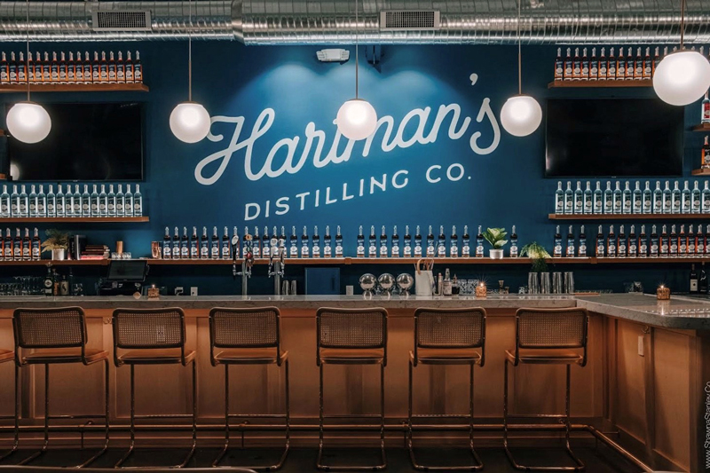 Hartman's Distillery bar, blue wall in the background with lit shelves lined with bottles.