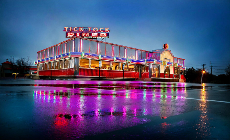 Outside of Tick Tock Diner, lit with Solid Apollo LED neon lights on a cloudy, rainy day.