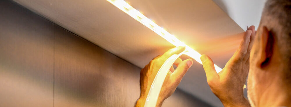 Man installing diffuser cover over an LED Strip in a recessed aluminum channel