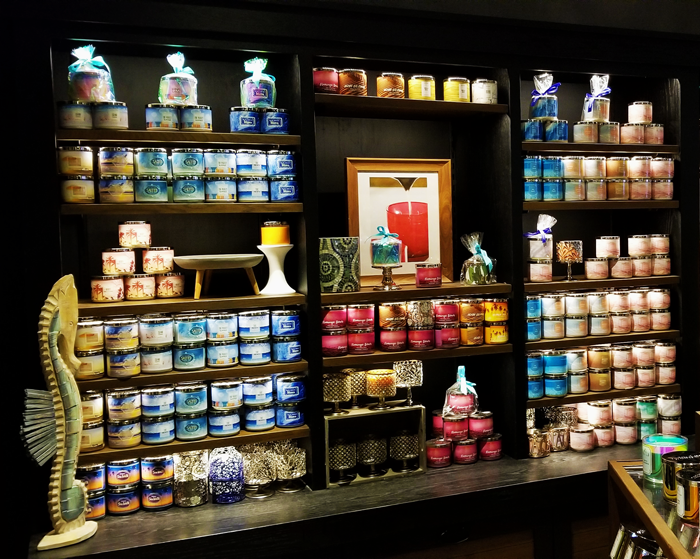 Candle store with vividly colored candles lining dark shelves lit with warm white LED strip shelf lighting